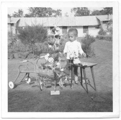 a very young PooterGeek stands by his Christmas tree in the compound in Nigeria